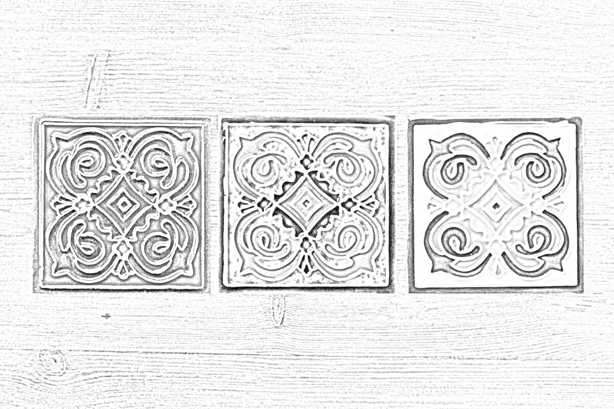 Три керамические плитки ручной работы на деревянном фоне: красная плитка с черно-белым узором, зеленая плитка с желто-черным узором и бело-синяя плитка с оранжево-синим узором