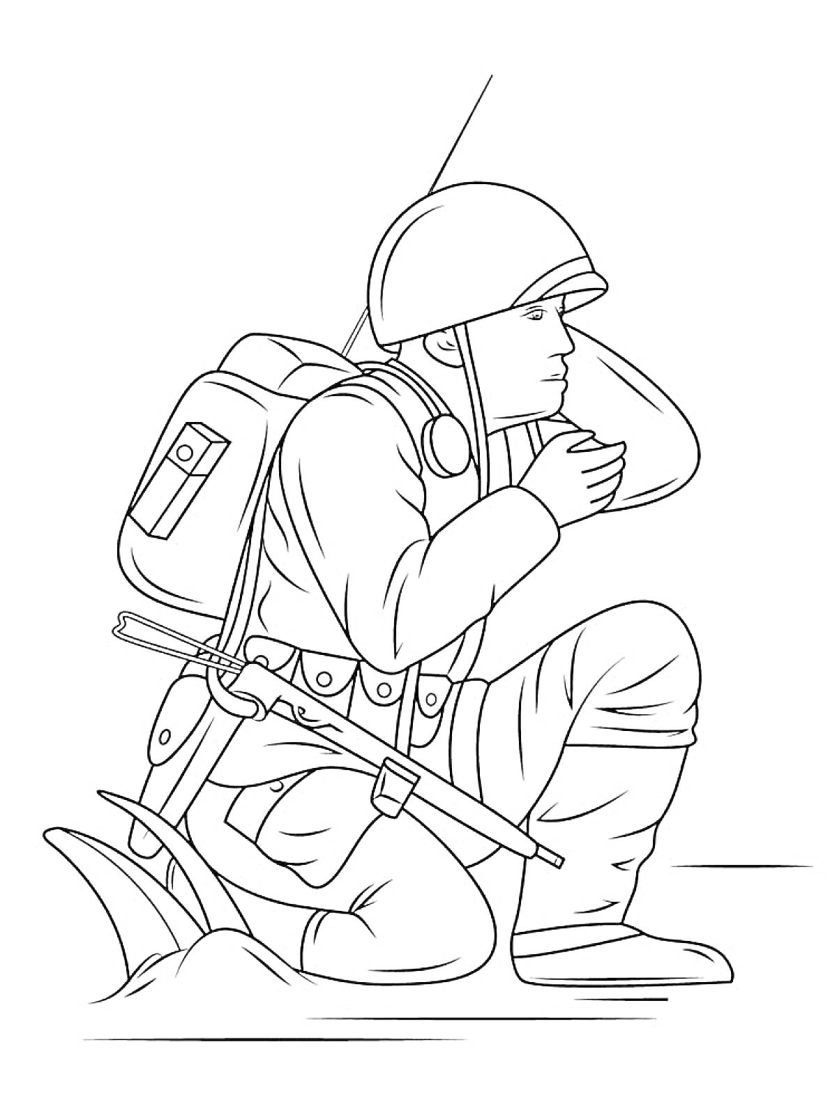 Солдат с пистолетом на коленях в каске и рюкзаке, держащий руку около лица
