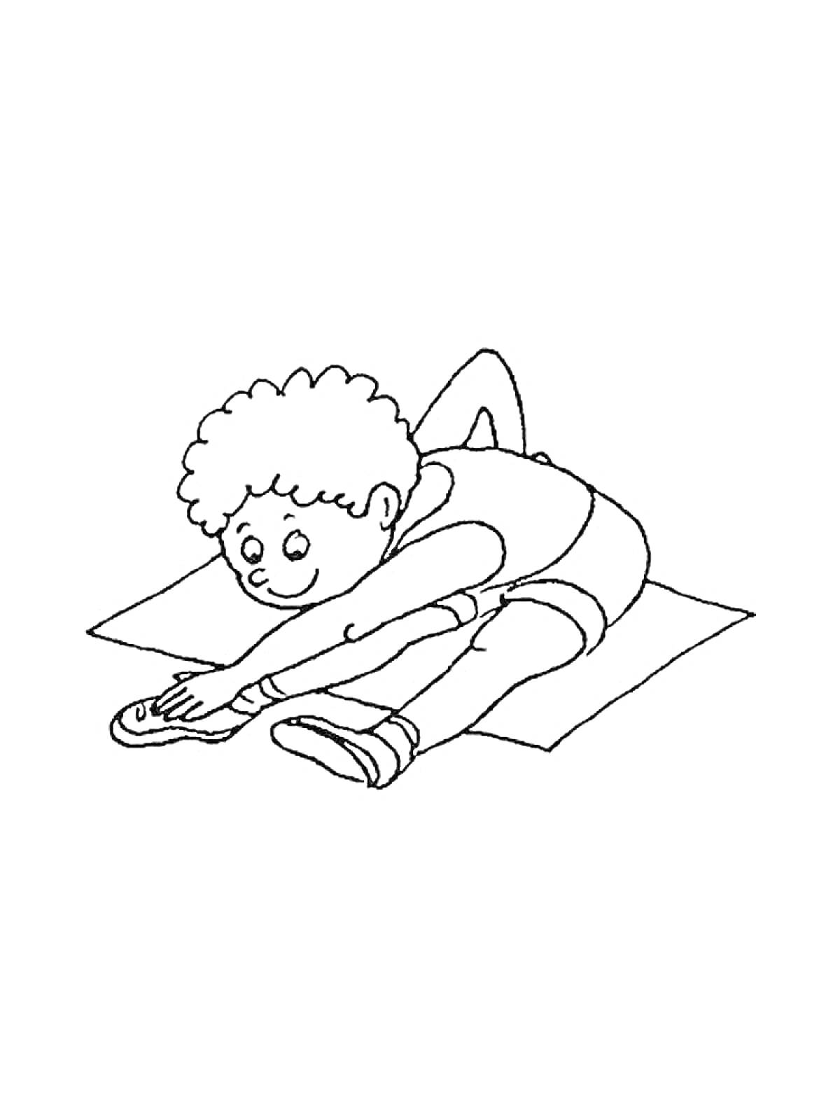 Мальчик делает растяжку на коврике